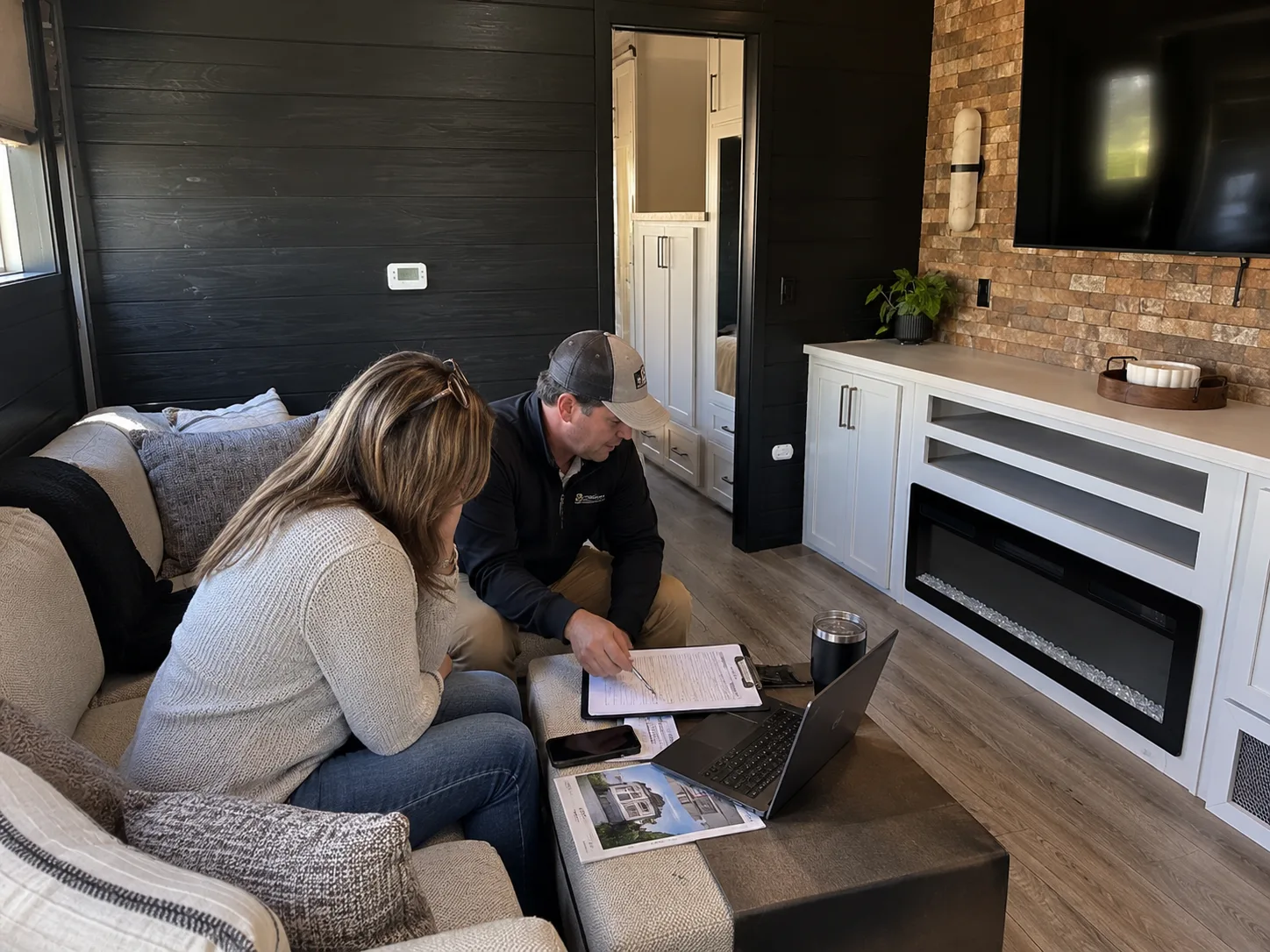 A couple going over park model paperwork with an Outpost Outfitters team member inside a Kropf park model