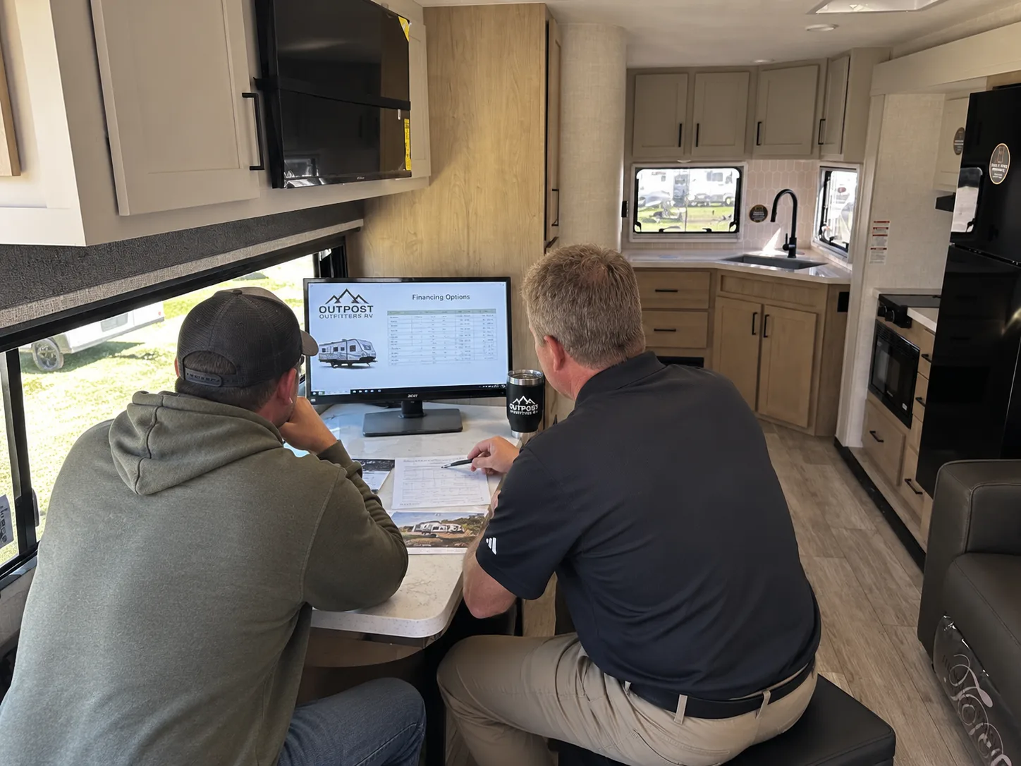 An Outpost Outfitters team member reviewing RV financing options on screen with a customer inside a motorhome