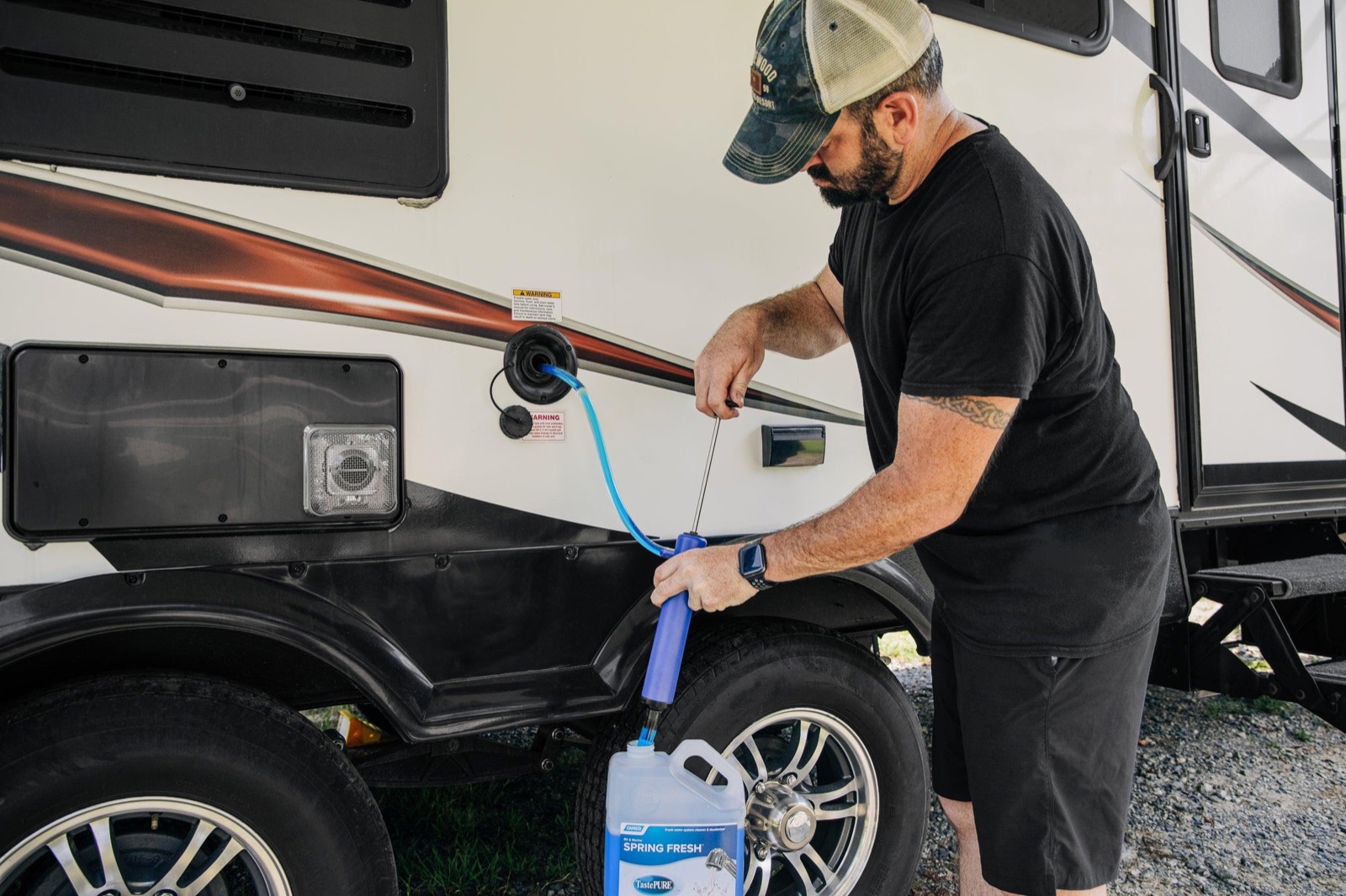 Outpost Outfitters technician pumping RV antifreeze into a travel trailer water inlet